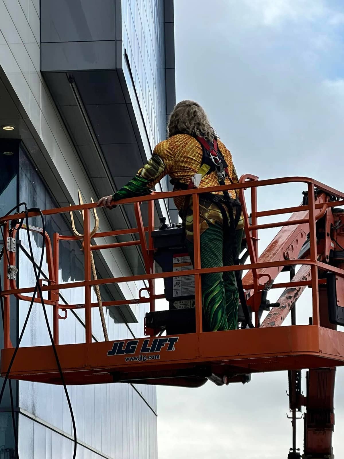 Technicien costumé en Aquaman lavant une façade